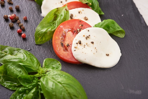 Free Photo fresh italian salad antipasto called caprese with buffalo mozzarella, sliced tomatoes and basil with olive oil. ingredients for vegetarian caprese salad. italian food. top view. rustic style.