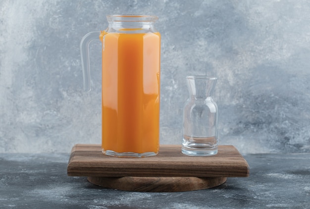 Fresh juice and empty glass on wooden board. 