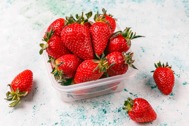 Fresh juicy strawberries in plastic lunch box on light