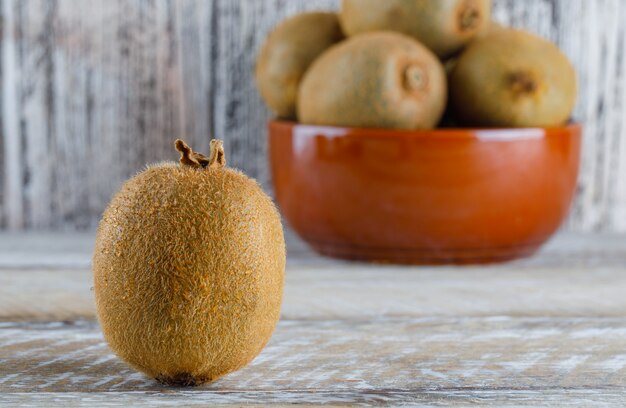 Fresh kiwi in a bowl side view on a wooden table