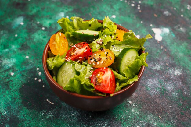 Fresh lettuce salad with yellow tomatoes, slices,cherry tomatoes,seeds bowl on dark, 