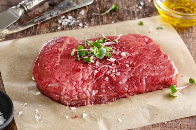 Fresh meat steak on old wooden board Dark background Closeup