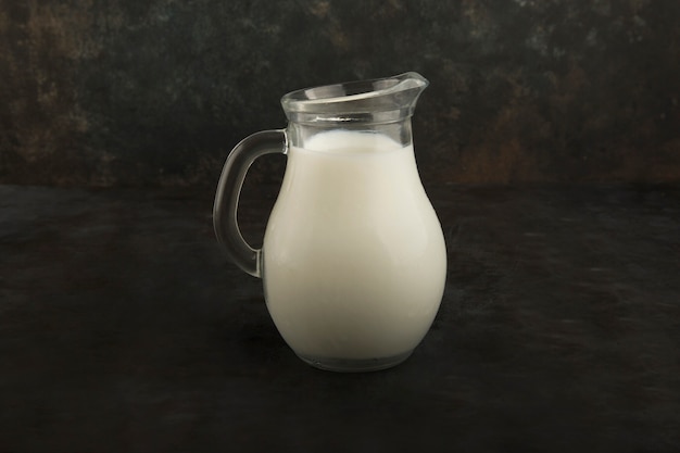 Fresh milk in a glass jar on black background