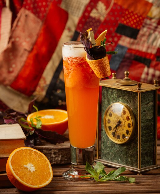 Fresh orange cocktail served in a glass with pipe and peeled orange skin and fresh mint leaves.