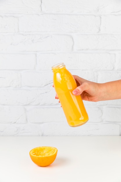 Free photo fresh orange juice bottle held by person