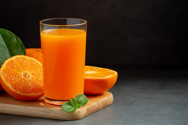 Free photo fresh orange juice in the glass on dark background