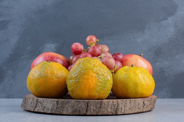 Fresh organic fruits on Wooden board. Tangerine, red grape and apple. 