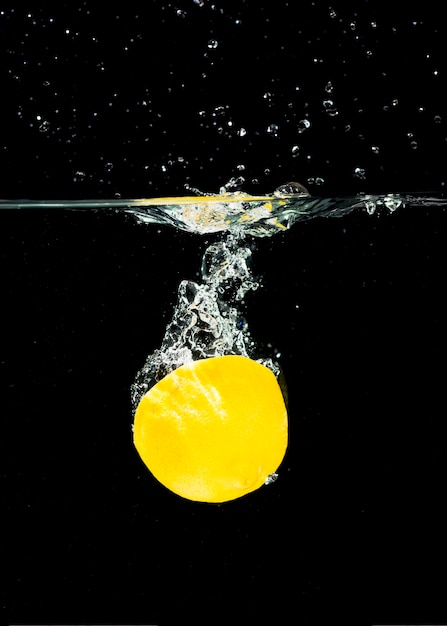 Free photo fresh organic halved lemon splashing into water