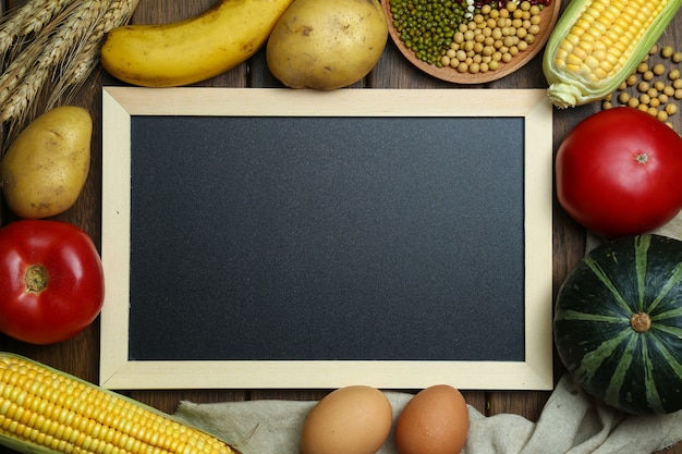 Free photo fresh organic vegetables,fruits,eggs,beans,and corns with blackboard on vintage wooden table