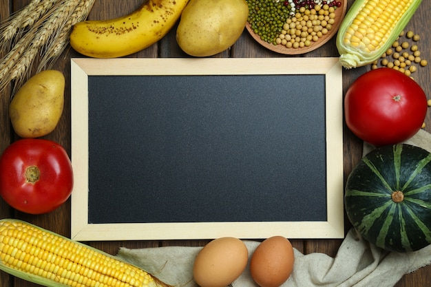 Free photo fresh organic vegetables,fruits,eggs,beans,and corns with blackboard on vintage wooden table