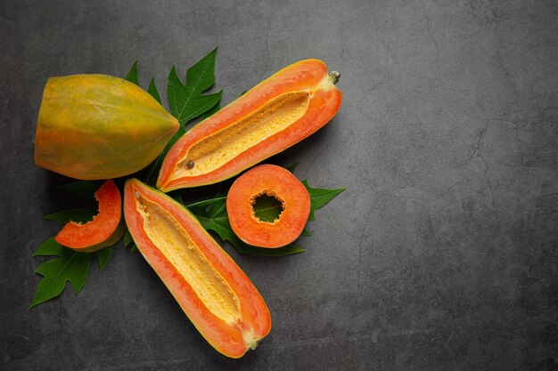 Free Photo fresh papaya, cut into half, put on dark floor