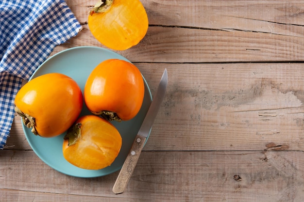 Free photo fresh persimmon fruit on wooden table