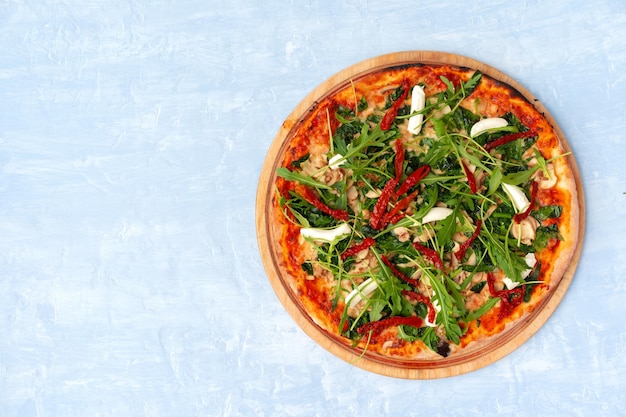 Fresh pizza with herbs and sun dried tomatoes on gray table