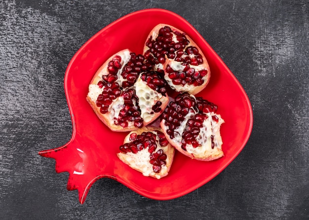 fresh pomegranate in red pomegranate shaped plate on dark