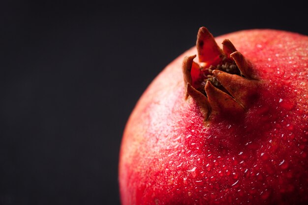 Fresh pomegranate with water droplets on a dark background