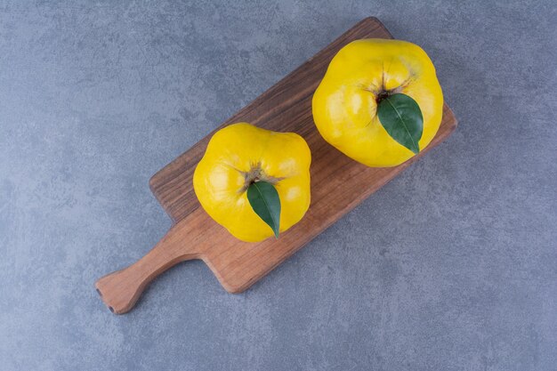 Fresh quinces on cutting board on marble table.