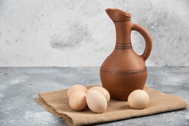 Fresh raw chicken eggs and antique bottle on marble surface.