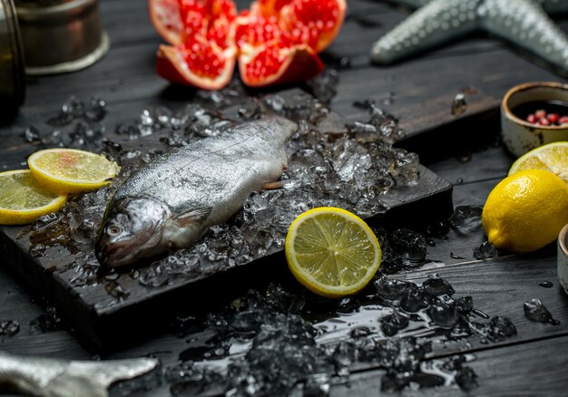 Fresh raw fish, lemon, pomegranate and ice cubes.