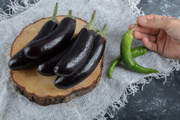 Fresh raw vegetables. Pile of eggplant and green pepper holding with hand.