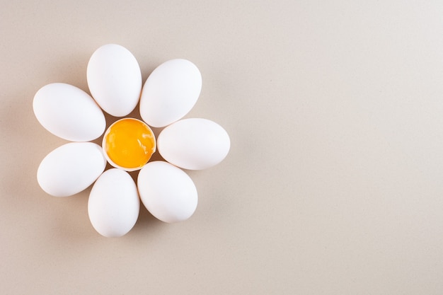 Free photo fresh raw white chicken eggs placed on beige table .