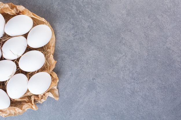 Fresh raw white chicken eggs placed on stone table .