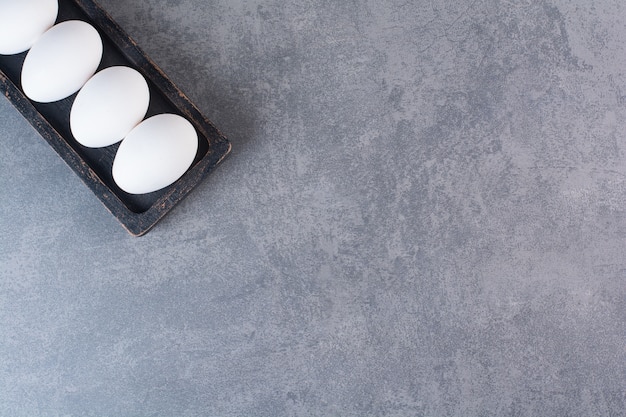 Free photo fresh raw white chicken eggs placed on stone table .