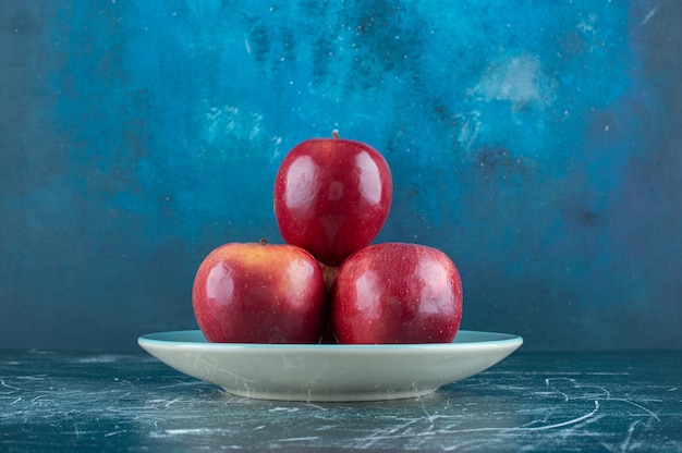 Fresh red apples on blue plate. 