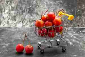 Free photo fresh red cherry fruit in shopping cart on gray background