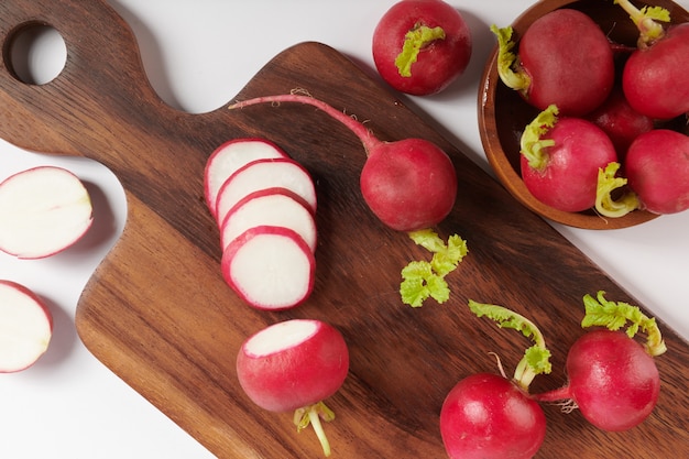 Fresh red radish on cutting board. Set of fresh whole small garden radish isolated on white surface. Top view. Flat lay. freshly picked from home growth organic garden. Food concept.