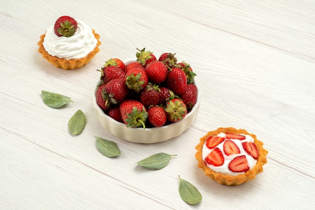 fresh red strawberries mellow and delicious berries inside plate with cakes on light desk