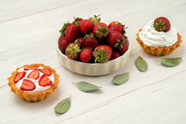 fresh red strawberries mellow and delicious berries inside plate with cakes on light desk