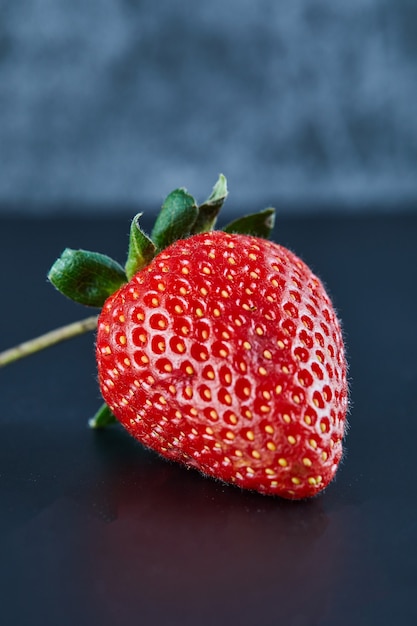 Fresh red strawberry on dark surface. Close up