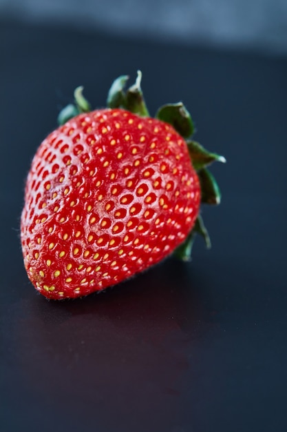 Fresh red strawberry on dark surface. Close up