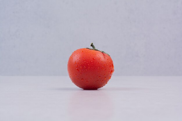 Fresh red tomato on white surface