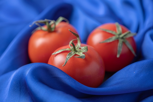 Free photo fresh red tomatoes on blue tablecloth .