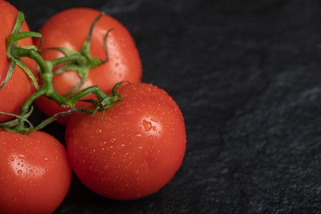 Fresh red tomatoes on dark surface