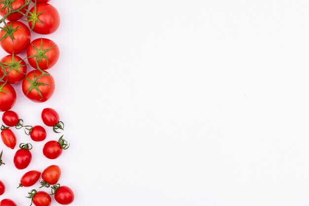 Fresh red tomatoes on the left of frame border white surface spreaded tomotoes