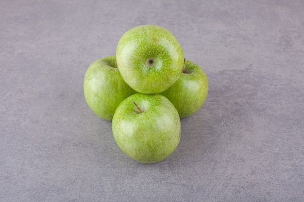 Fresh ripe green apples placed on a stone surface.