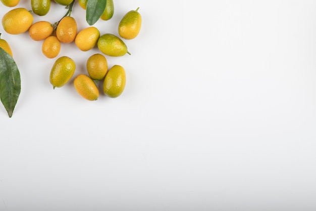 Free photo fresh ripe kumquats with leaves on white.