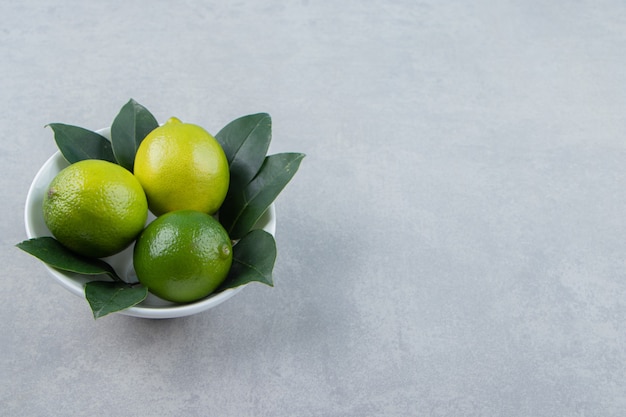 Fresh ripe limes in white bowl. 