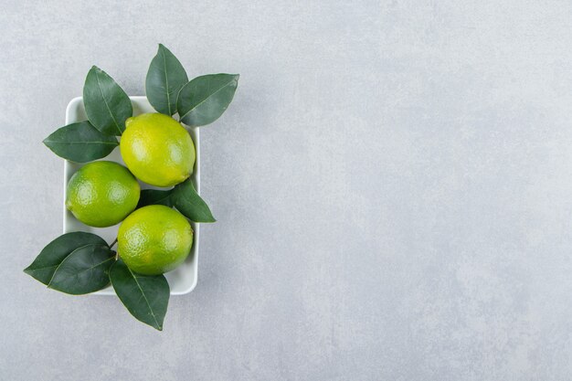 Fresh ripe limes on white plate. 