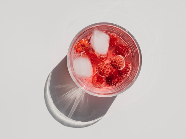 Free photo fresh ripe raspberries and raspberry juice in a glass with ice cubes