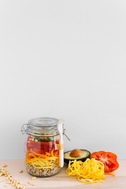 Fresh salad of avocado; tomato; corn seed and noodles in jar