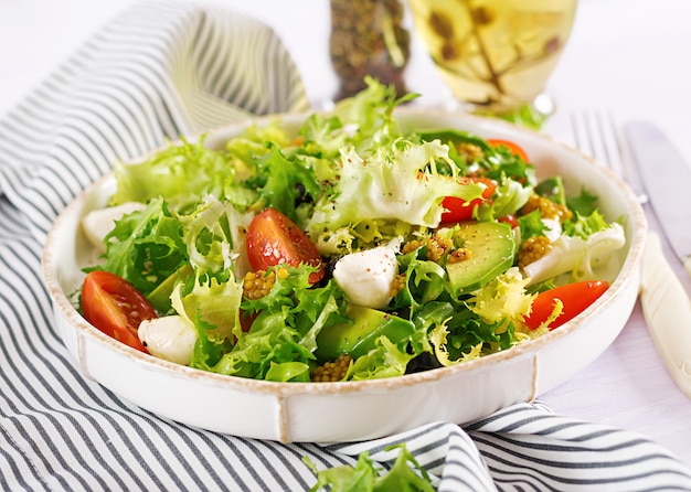 Free photo fresh salad with avocado, tomato, olives and mozzarella in a bowl.  fitness food. vegetarian meal.