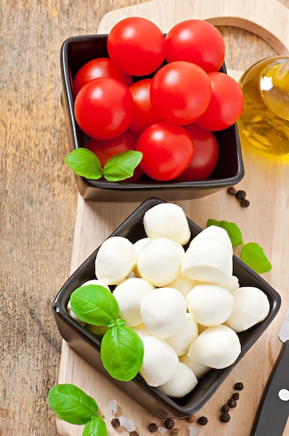 Free photo fresh salad with cherry tomatoes, basil, mozzarella and black olives.