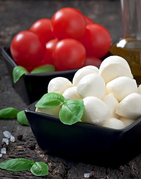 Free photo fresh salad with cherry tomatoes, basil, mozzarella and black olives.