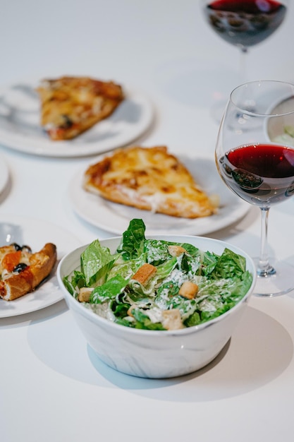 Fresh salad with pizza slices on the plates and a glass of wine