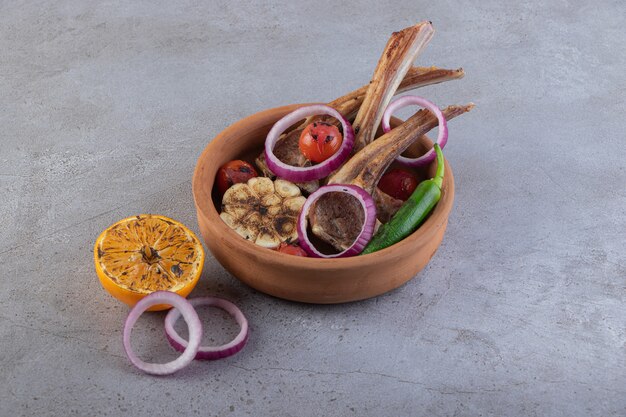 Fresh sliced meat with fresh vegetables placed on a stone table. 