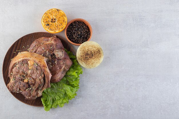 Fresh sliced meat with fresh vegetables placed on a stone table. 