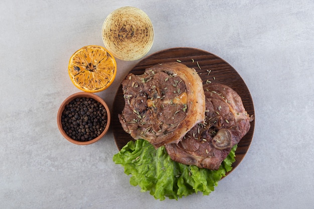 Fresh sliced meat with fresh vegetables placed on a stone table. 